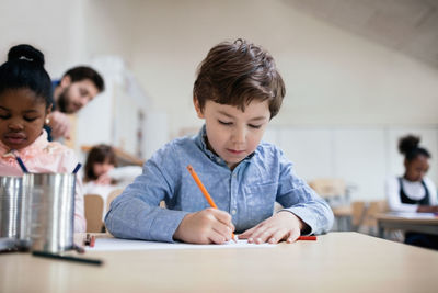 Serious boy studying while sitting in classroom at school