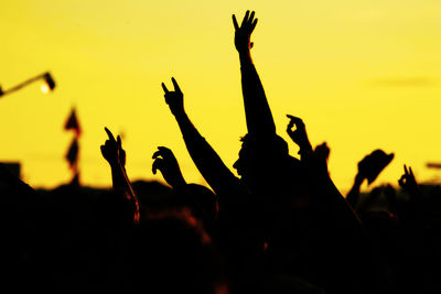 Silhouette people at music concert against sky during sunset