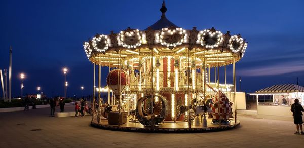 Illuminated carousel against sky at night