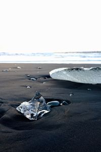 Close-up of stones on beach against clear sky