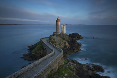 Lighthouse amidst sea against sky