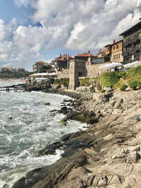 Bridge over sea by buildings against sky