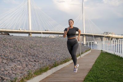 Smiling woman jogging on footpath