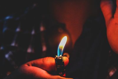 Close-up of hand holding lit candle