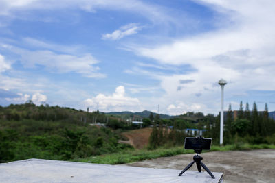 Rear view of person photographing car on street against sky