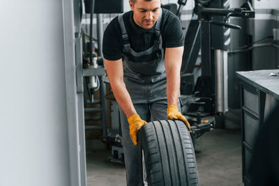 Close up view of wheel. man in uniform is working in the auto service.