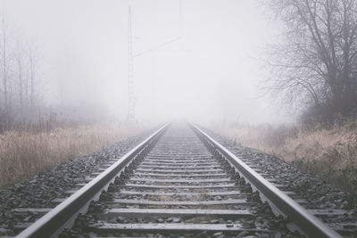 Railroad track against sky during foggy weather