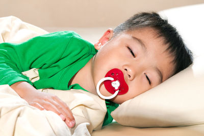 Close-up portrait of boy lying on bed at home