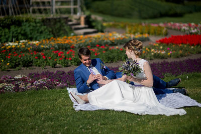 Bride and bridegroom on picnic blanket at park