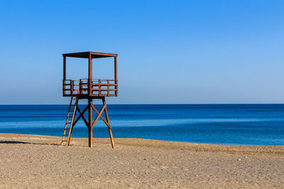 Lifeguard hut on beach against clear blue sky