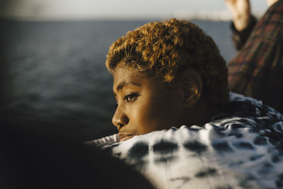 Young non-binary person looking away at pier