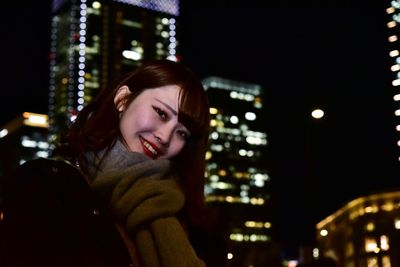 Portrait of smiling young woman in city at night
