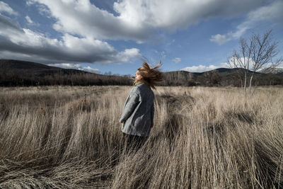 Rear view of woman standing on field against sky