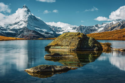 Scenic view of lake by snowcapped mountains against sky