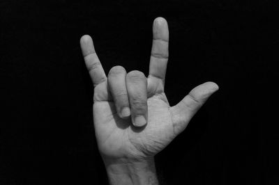 Cropped hand of man gesturing against black background