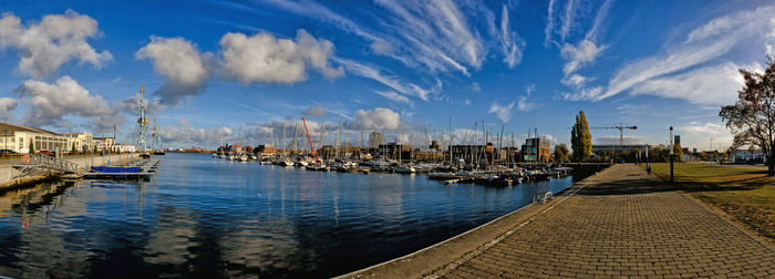 Panoramic view of harbor by buildings against sky