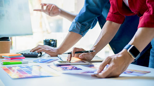 Midsection of people holding paper while standing on table