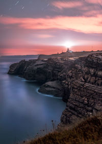 Rock formation on sea against sky during sunset