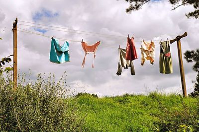 Clothes drying on clothesline on field against sky