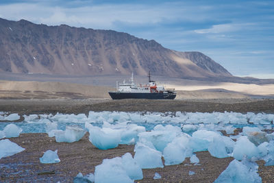 Nautical vessel on snowcapped mountain against sky