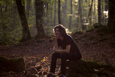 Young woman sitting on tree trunk in forest