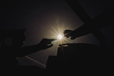 Silhouette hand holding sun during sunset