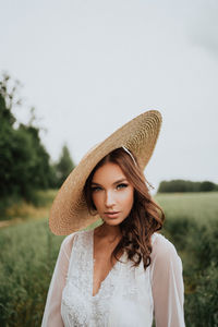 Portrait of beautiful young woman wearing hat against sky