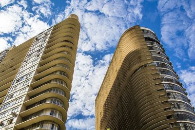 Low angle view of skyscrapers against cloudy sky