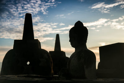 Silhouette statue of temple against cloudy sky