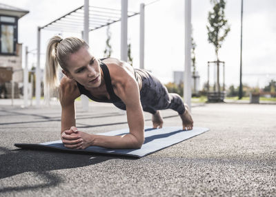 Young sportswoman practicing plank pose on exercise mat
