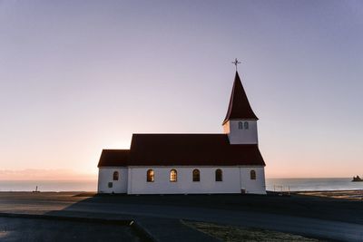 Lighthouse by sea against sky during sunset