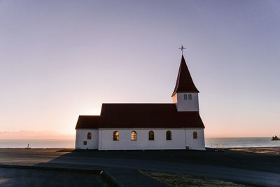 Church by sea against sky during sunset