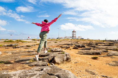 Rear view of man standing on rock against sky