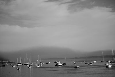 Boats in sea against cloudy sky