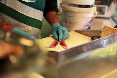 Midsection of man cutting meat