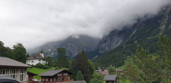 Houses amidst trees and buildings against sky