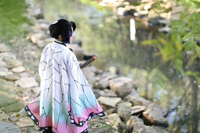 Side view of young woman standing against plants