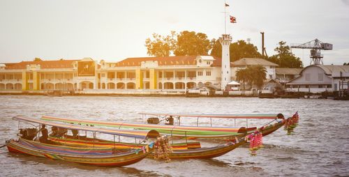 Boats moored in river against buildings