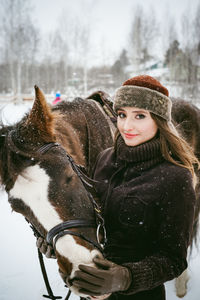 Close-up portrait of beautiful woman with horse on field during snowfall