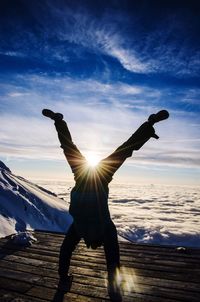 Silhouette man doing handstand at observation point during winter