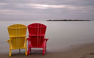 2 colorful chairs overlooking the ocean beyond - wallpapers