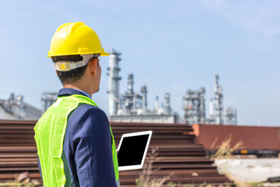 Man in reflective clothing using digital tablet while standing outdoors