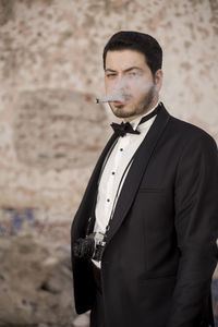 Portrait of man smoking while standing outdoors