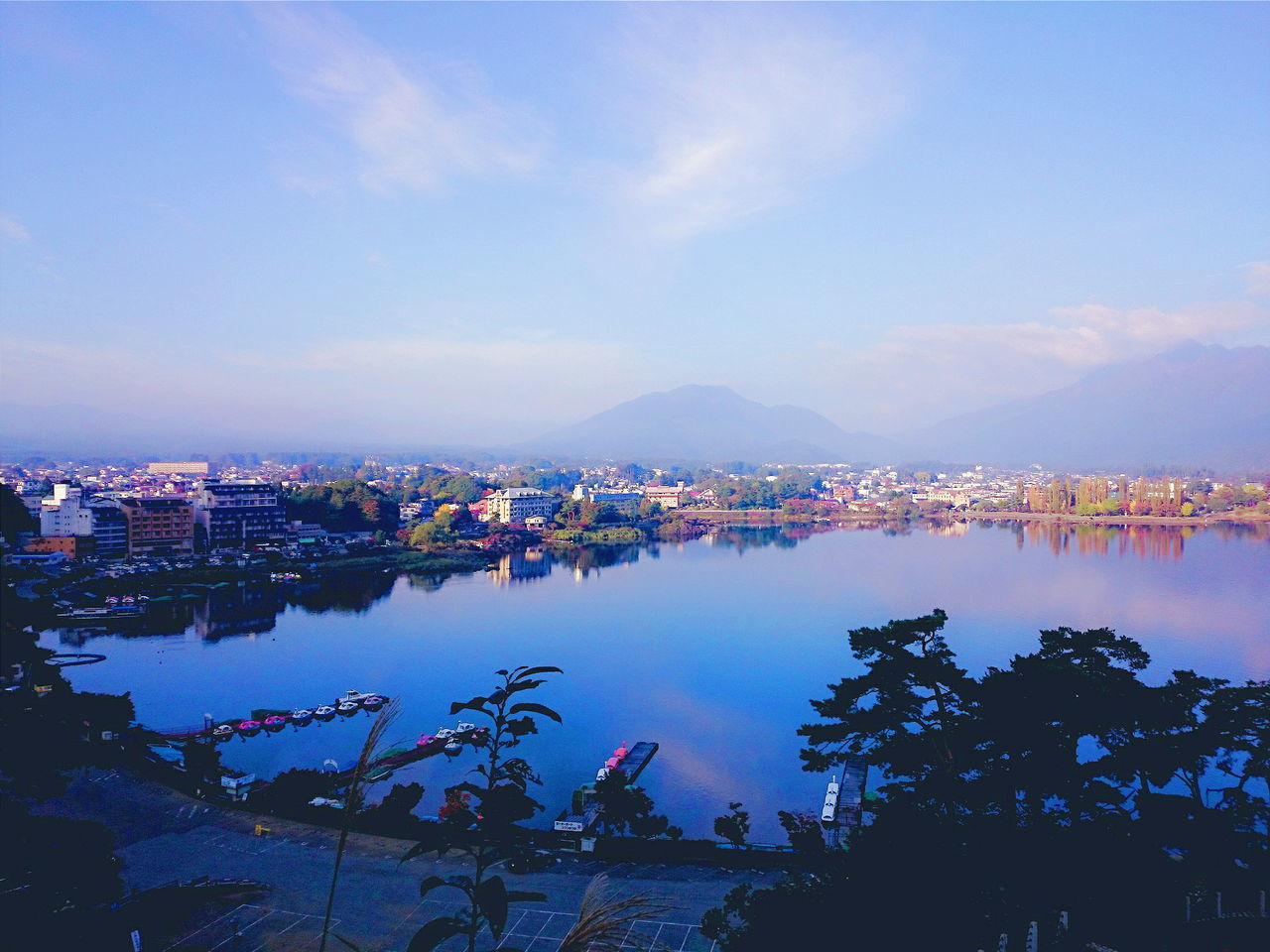 architecture, built structure, building exterior, water, sky, city, blue, cityscape, high angle view, river, residential structure, residential district, sea, reflection, residential building, town, crowded, mountain, outdoors, nautical vessel