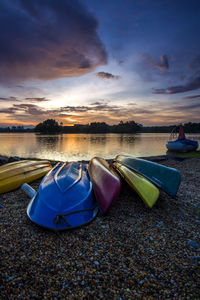 Boats moored at beach against sky during sunset