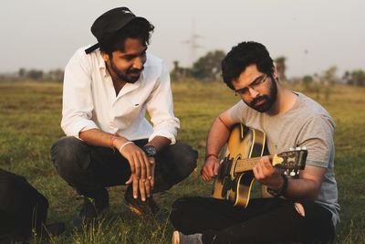 Young man playing guitar on field