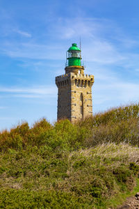 Lighthouse on field against sky