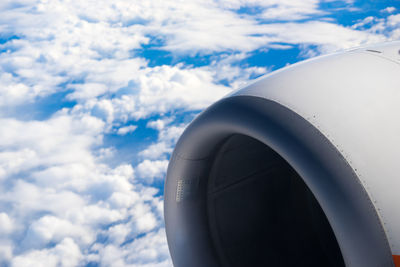 Close-up of airplane jet engine against cloudy sky
