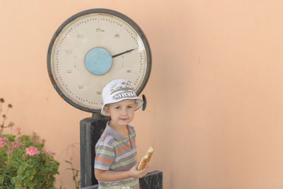 Portrait of cute boy standing against wall