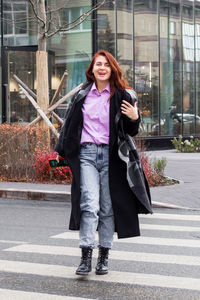 Attractive smiling business woman in casual clothing is walking in a city. 